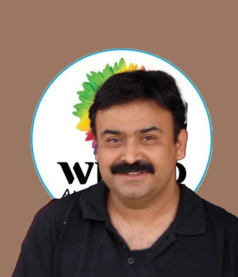 Abhijit Bhaduri smiling in front of a colorful company logo. Could this be the Chief Learning Officer, or perhaps the Chief what? The mystery continues!